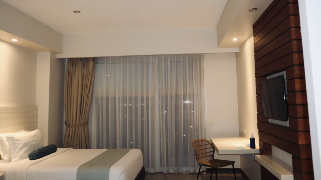 Kamar hotel budget dengan tempat tidur rapi dan TV, cocok untuk staycation hemat di Purwokerto