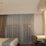Kamar hotel budget dengan tempat tidur rapi dan TV, cocok untuk staycation hemat di Purwokerto