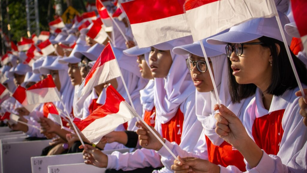 Orang-orang membawa bendera Indonesia dalam perayaan hari nasional