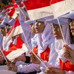Orang-orang membawa bendera Indonesia dalam perayaan hari nasional